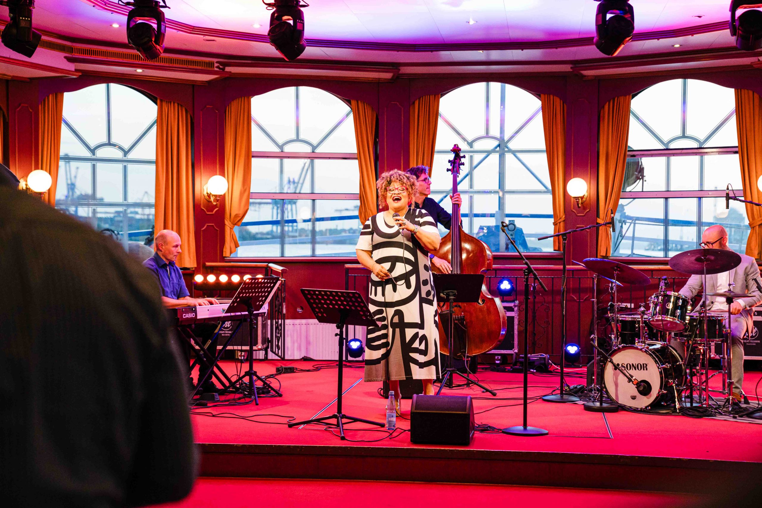 Live-Jazz-Performance auf der Winter Jazz Cruise in Hamburg: Sängerin mit Band auf der Bühne der MS Louisiana Star, stimmungsvolles Ambiente mit Blick auf den Hamburger Hafen.